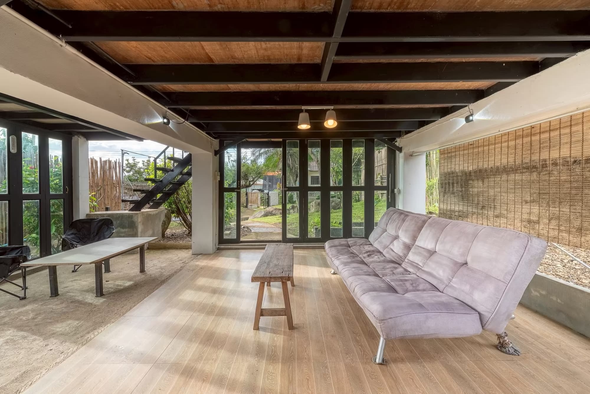 365 Vila Connect Pai open-air garden lounge with grey sofa bed, wooden benches and folding glass doors opening to the garden