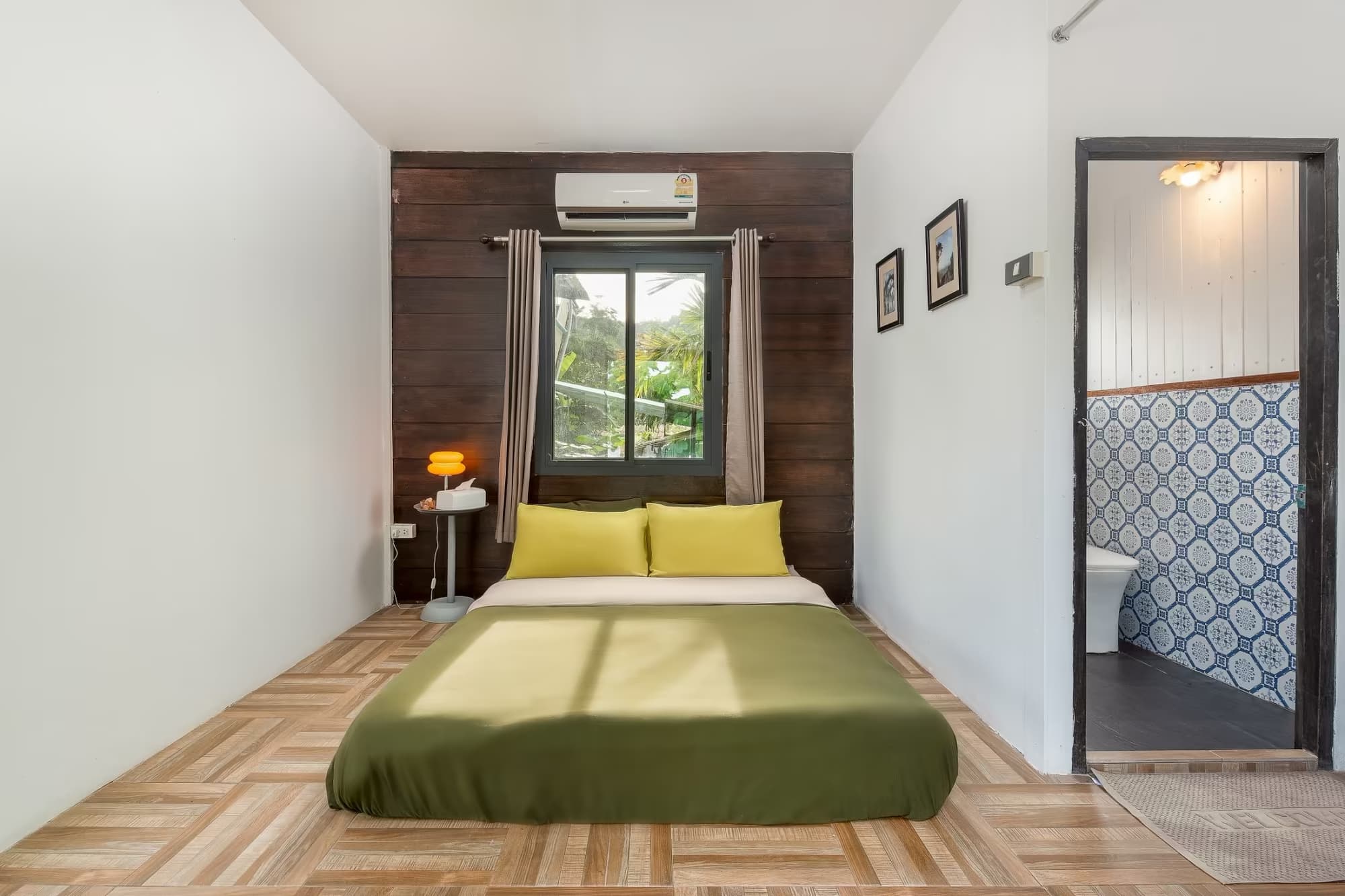 365 Vila Connect Pai air-con ensuite bedroom with green bed, yellow pillows and patterned-tile bathroom