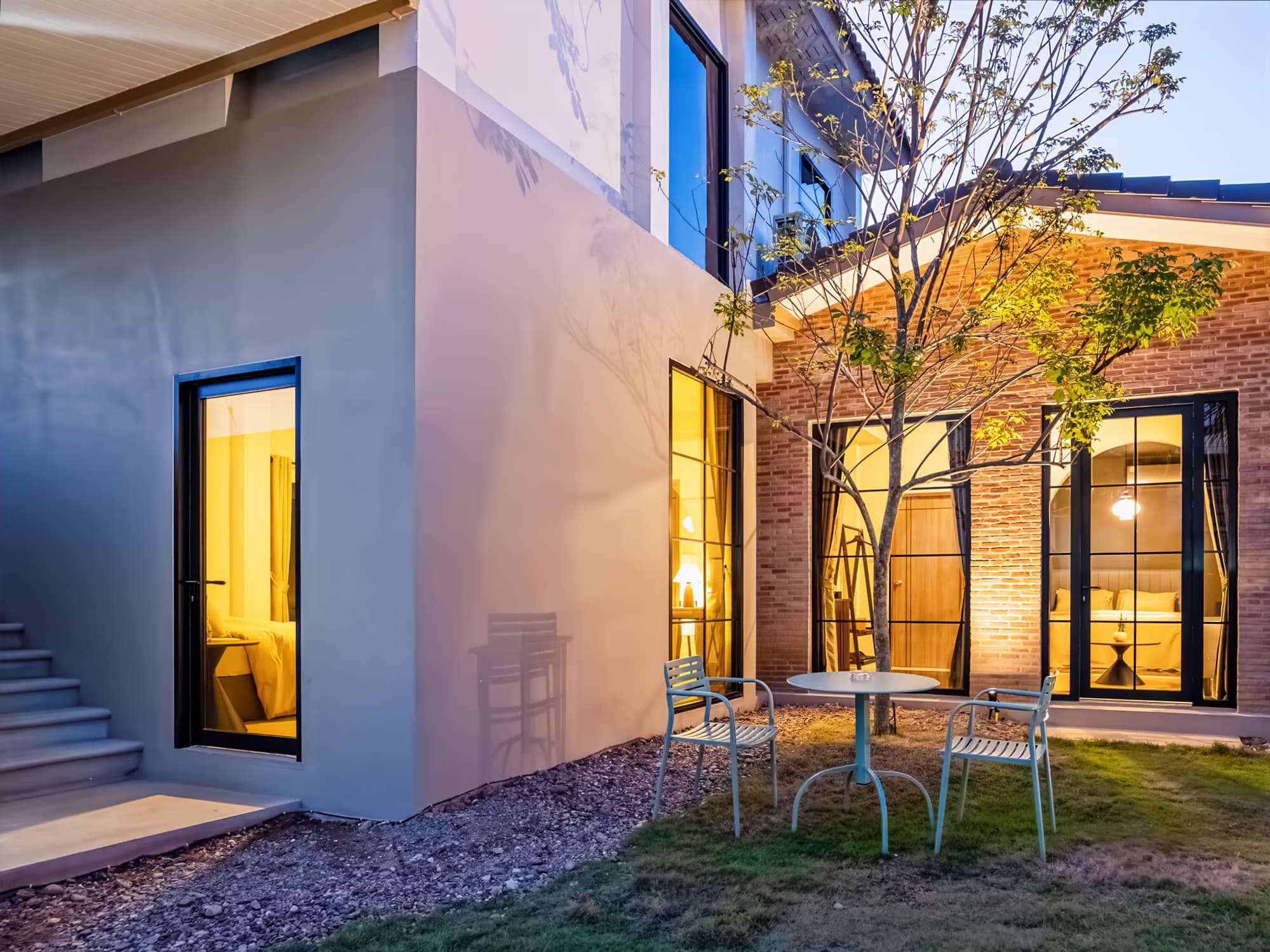 The Arch Casa design hotel Pai modern villa courtyard with glowing brick walls and bistro table garden at dusk