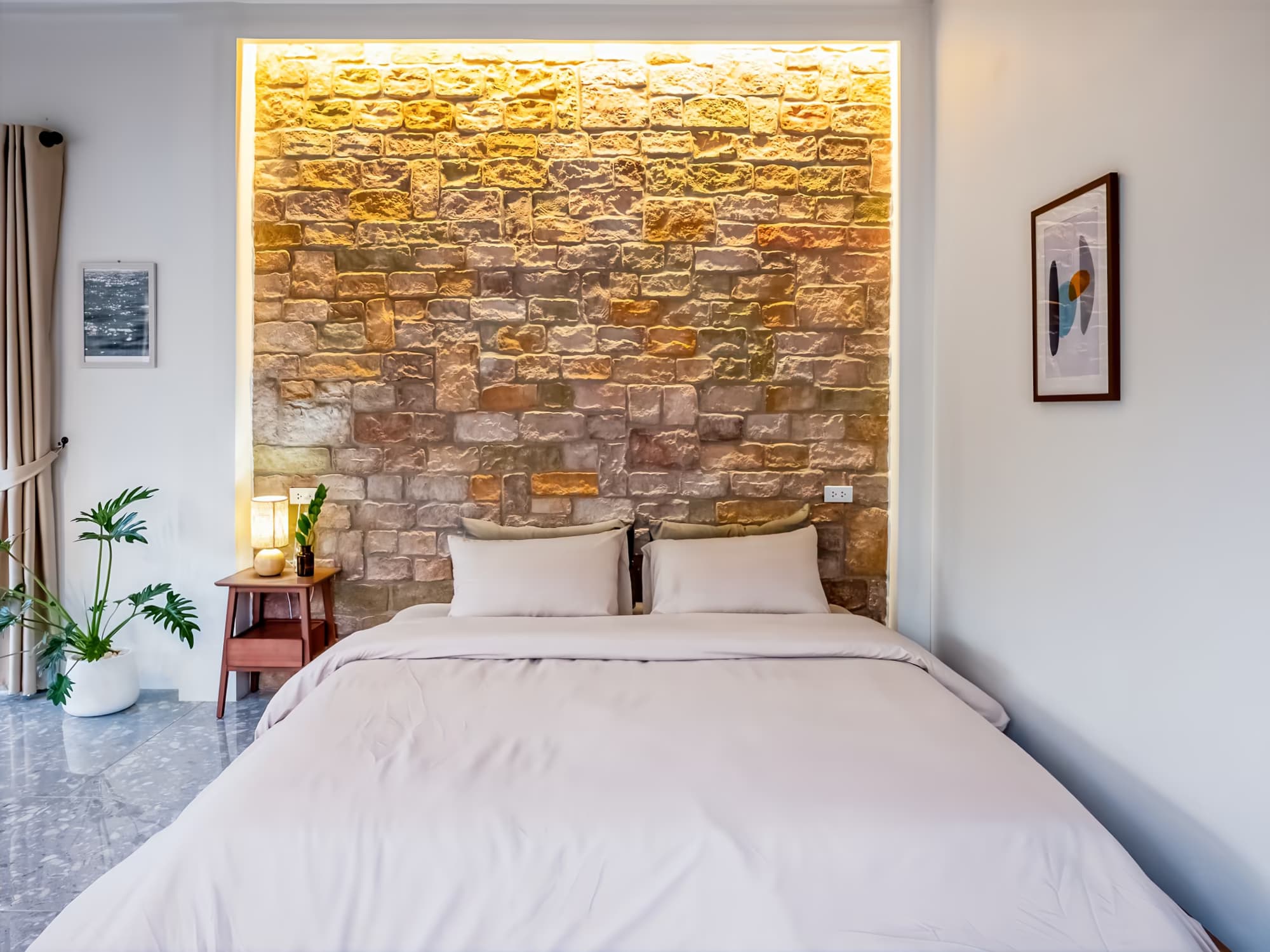 The Arch Casa Pai Executive Suite bedroom with backlit natural stone feature wall and plush king bed