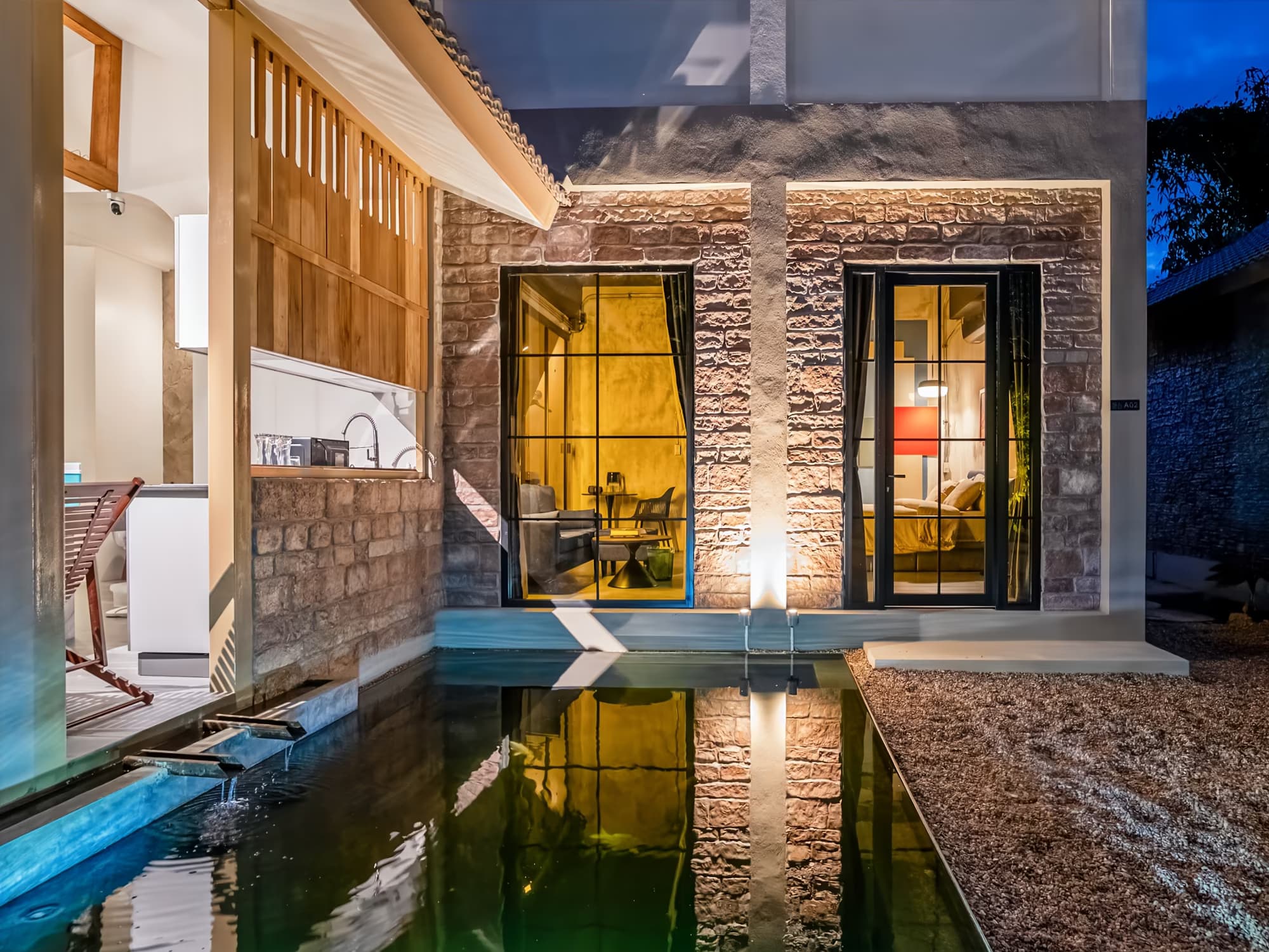 The Arch Casa Pai Studio with Garden View villa exterior at dusk with stone facade glowing windows and reflecting koi pond