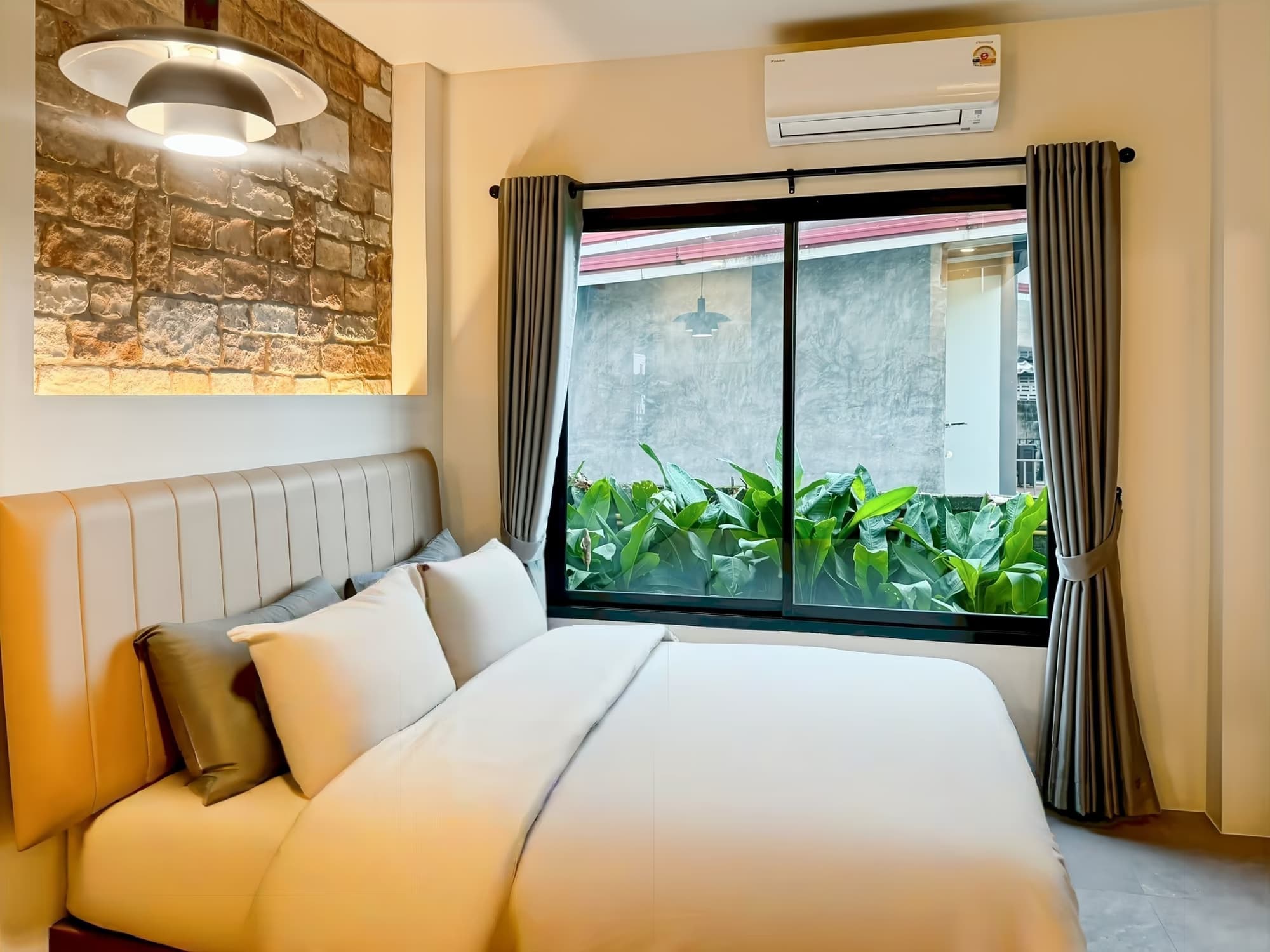 The Arch Casa Pai Standard Studio bedroom with leather headboard, stone art panel and window framing garden greenery