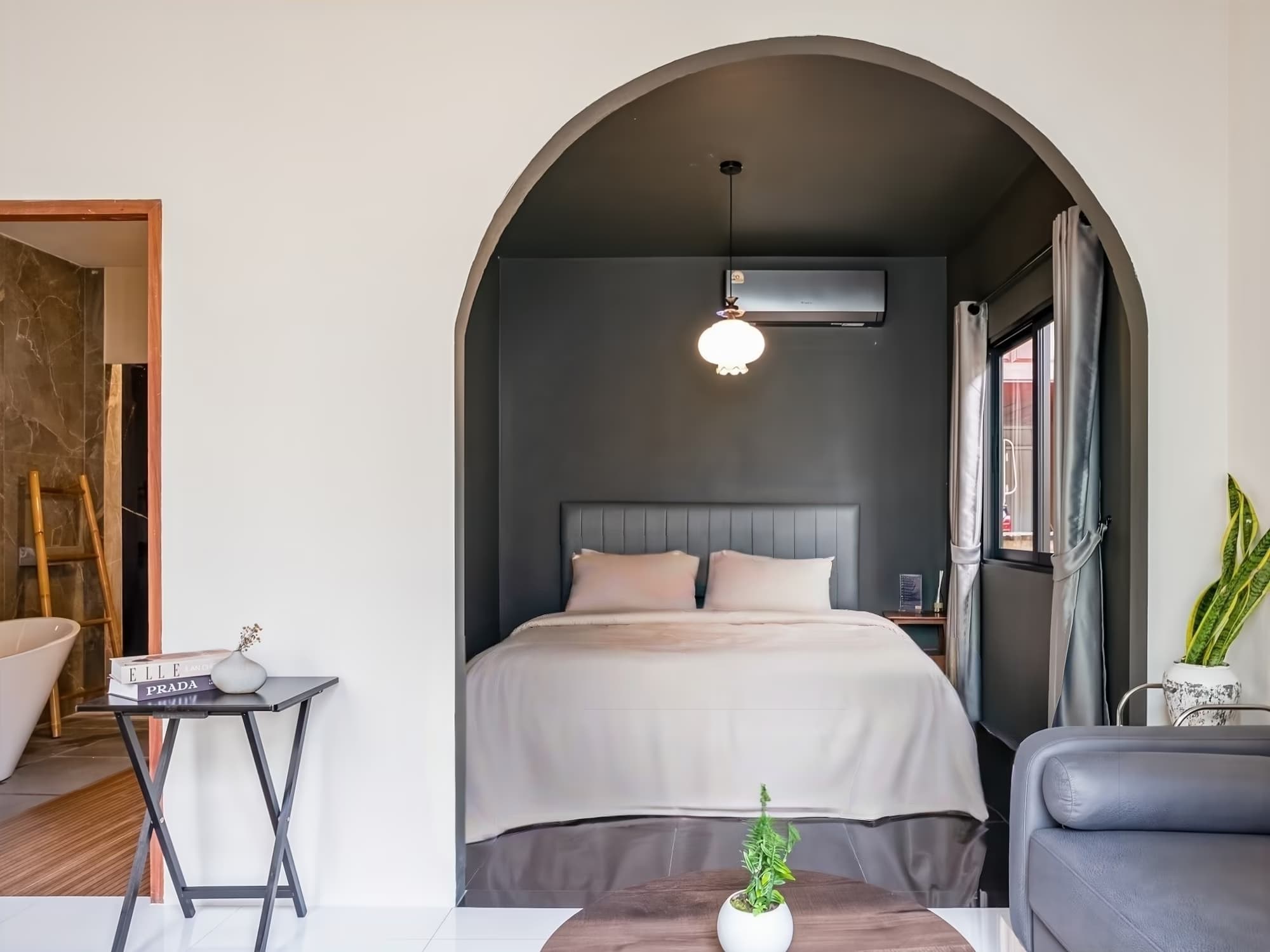 The Arch Casa Pai Deluxe Double Room with Bath, arched alcove bedroom with charcoal feature wall, pendant light and open bathtub view