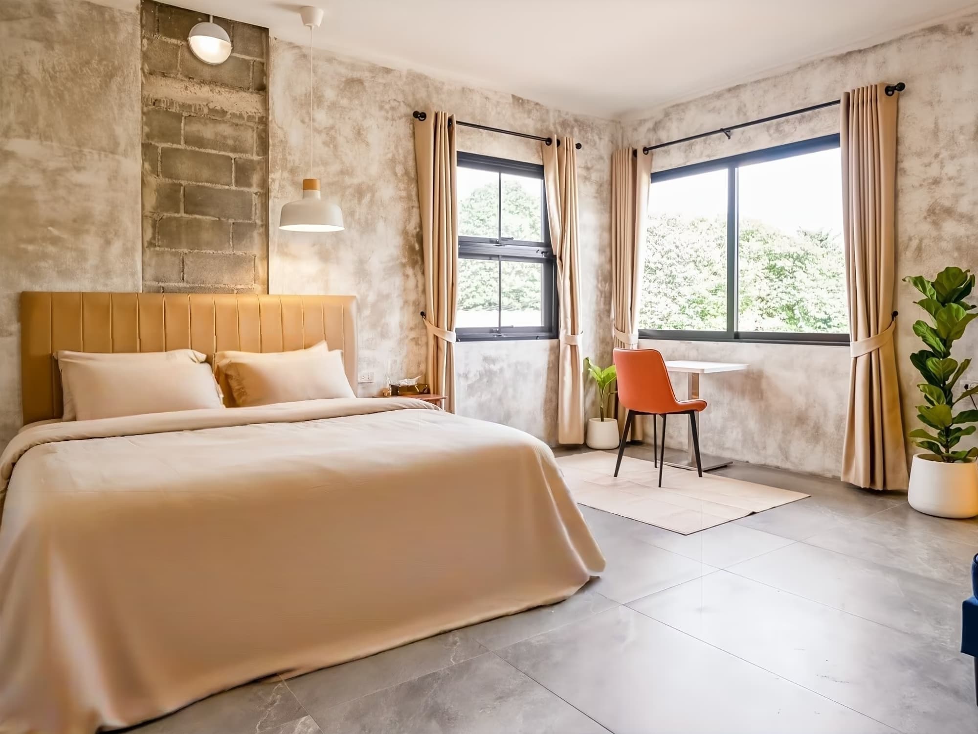 The Arch Casa Pai Superior Studio bedroom with queen bed, polished concrete walls, twin windows and orange desk chair