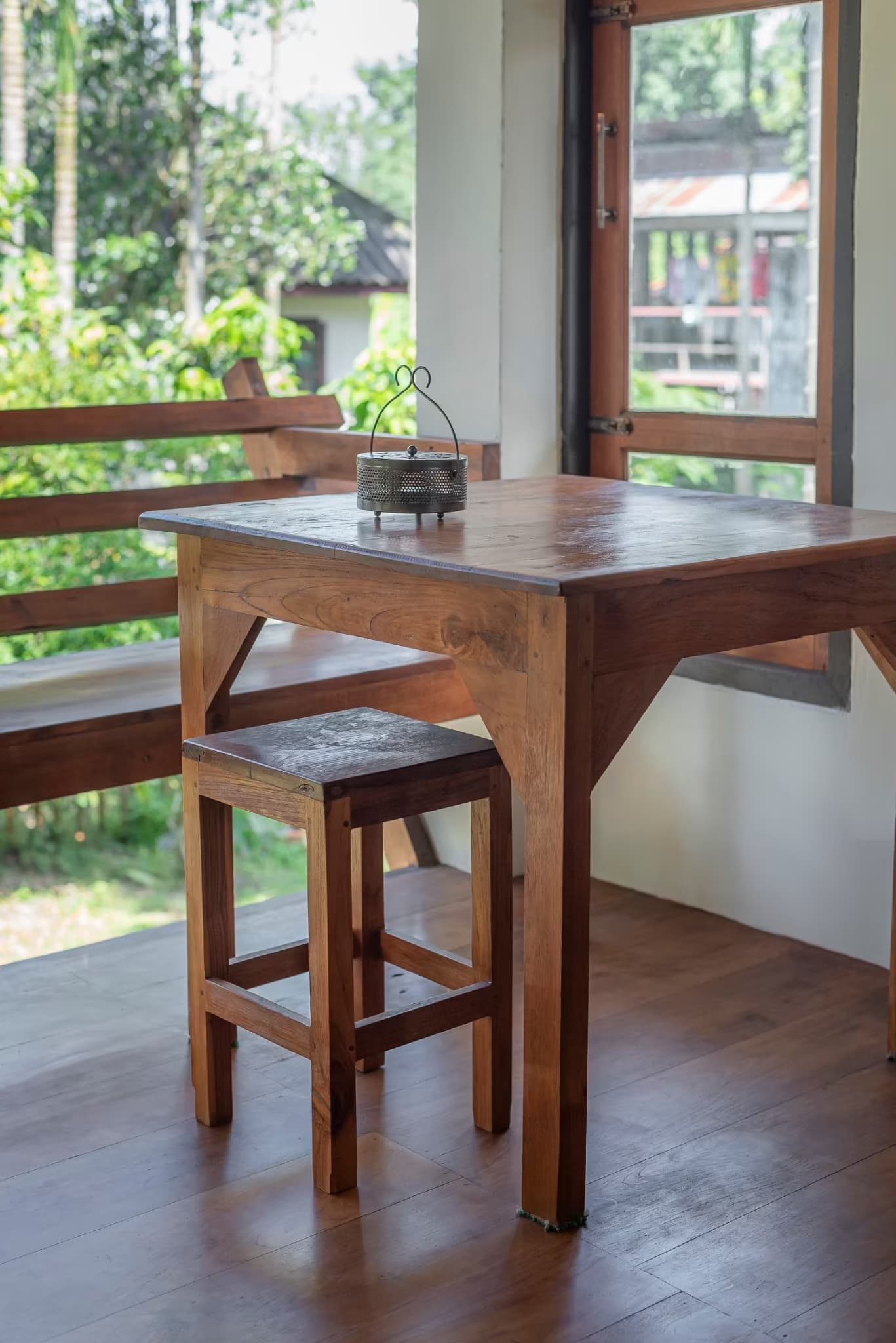 Teak work table and stool beside a large window overlooking lush betel palm garden at Betel Palm Village villa in Pai, Thailand