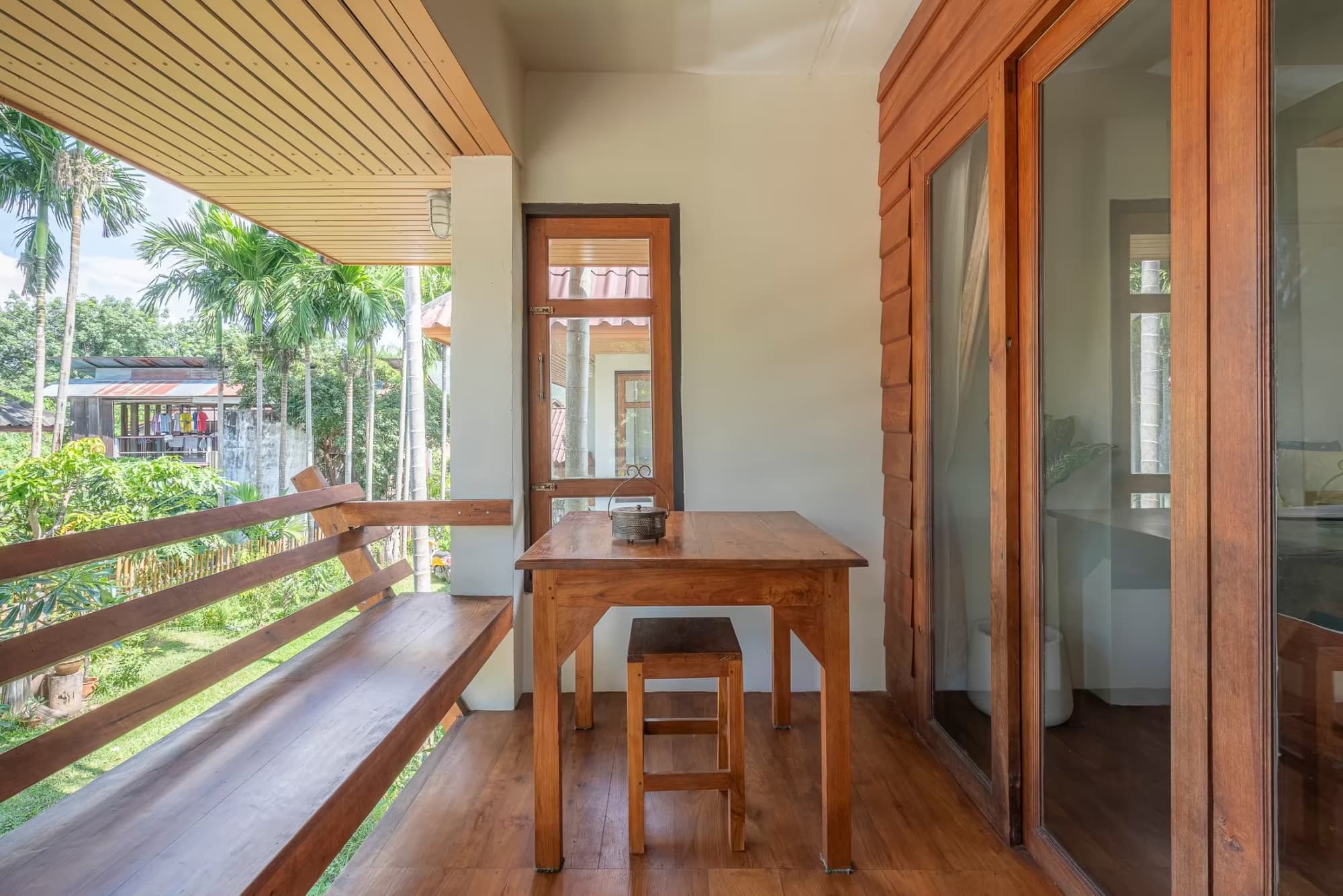 Private balcony workspace with wooden desk and stool overlooking palm trees at Betel Palm Village nature villas in Pai