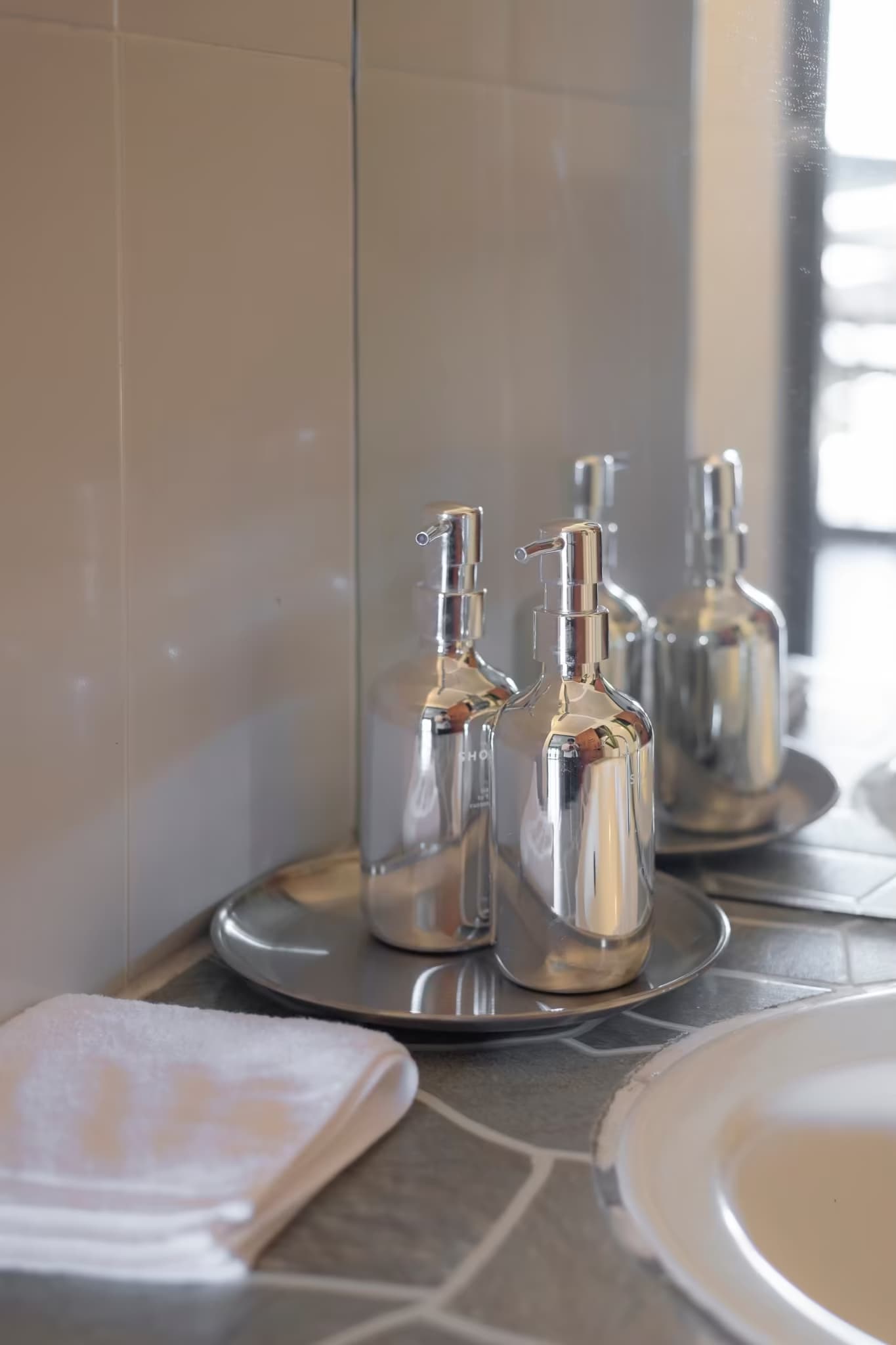 Ensuite bathroom vanity with chrome soap dispensers, tray and clean towels at Betel Palm Village in Pai