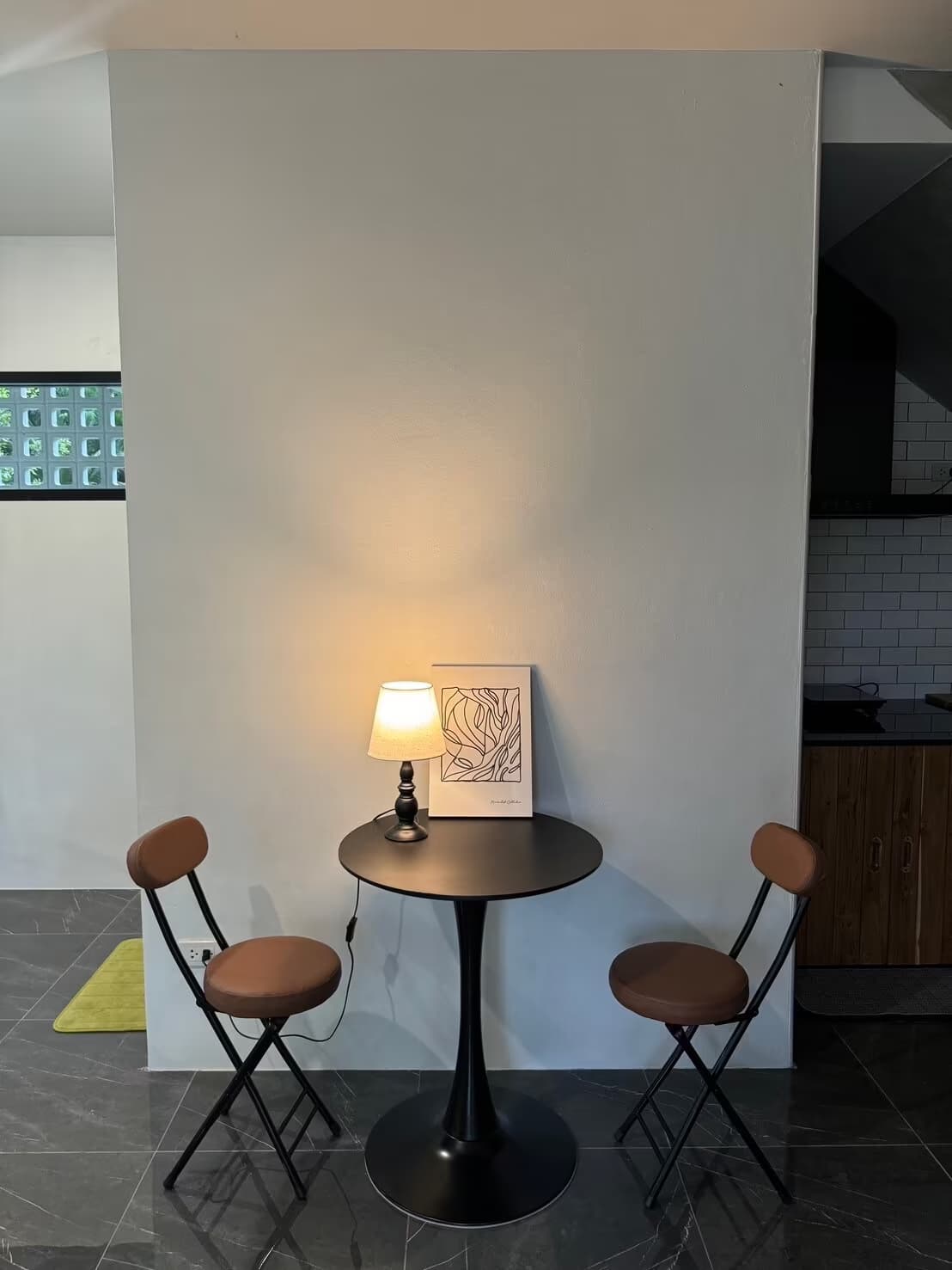 Eden Villa in Pai compact dining nook with round bistro table, two leather stools, lamp and tiled kitchen beside it
