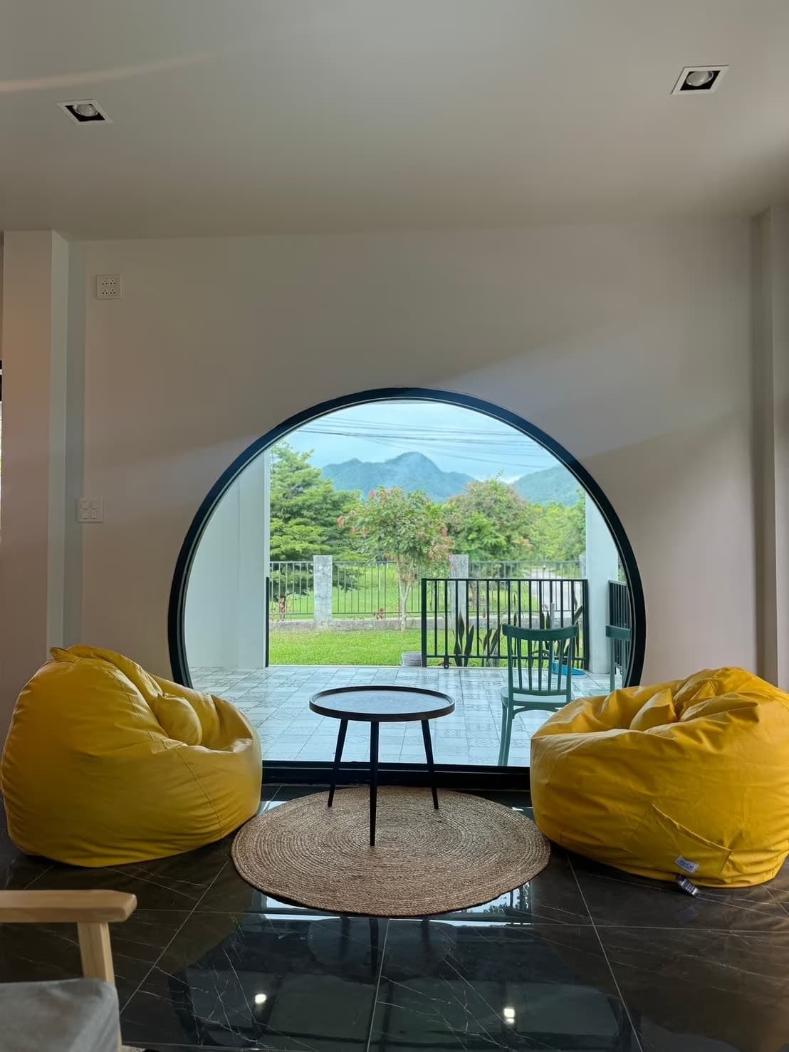 Eden Villa Pai relaxing lounge with yellow bean bags facing a round picture window framing Pai mountain and garden view
