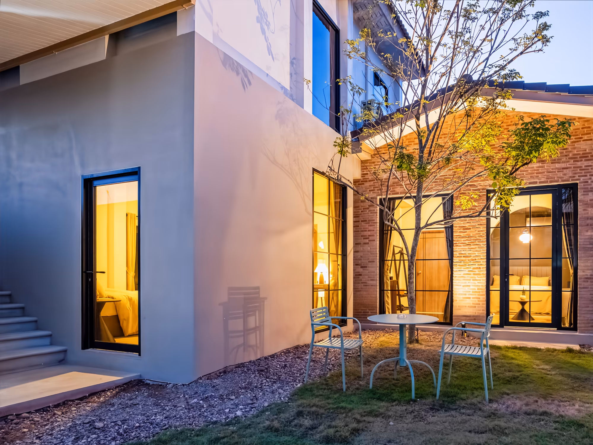 The Arch Casa design hotel Pai modern villa courtyard with glowing brick walls and bistro table garden at dusk