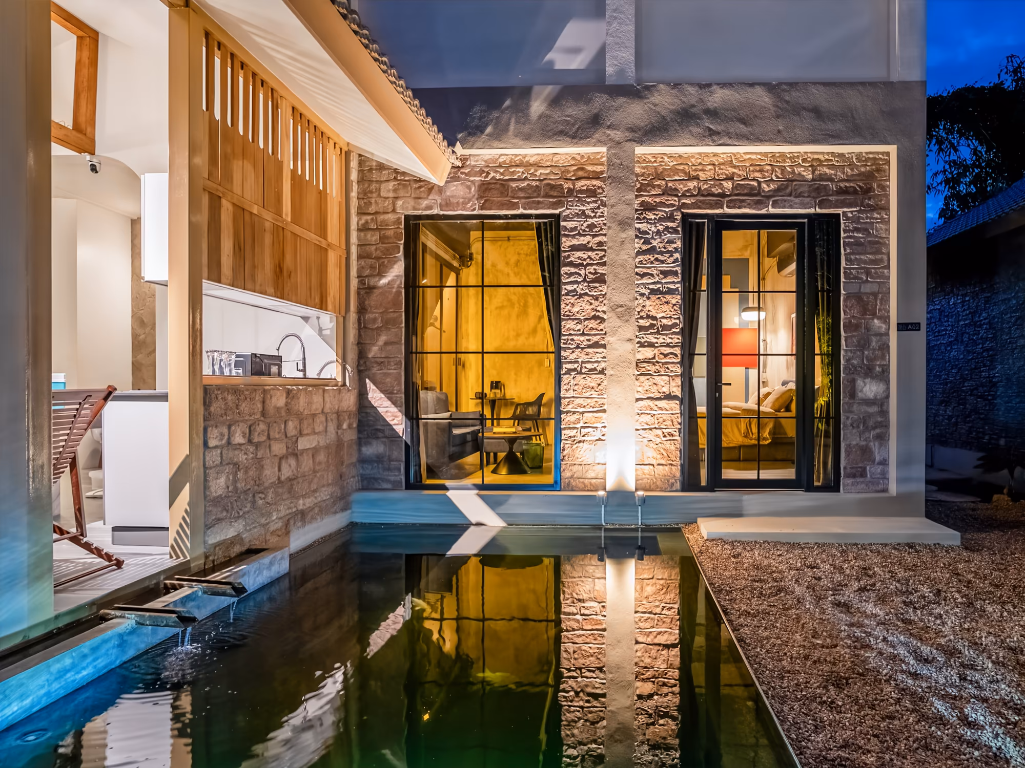 The Arch Casa Pai Studio with Garden View villa exterior at dusk with stone facade glowing windows and reflecting koi pond