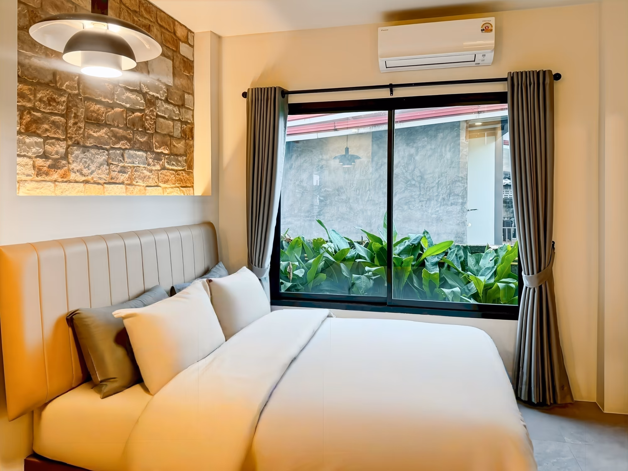 The Arch Casa Pai Standard Studio bedroom with leather headboard, stone art panel and window framing garden greenery