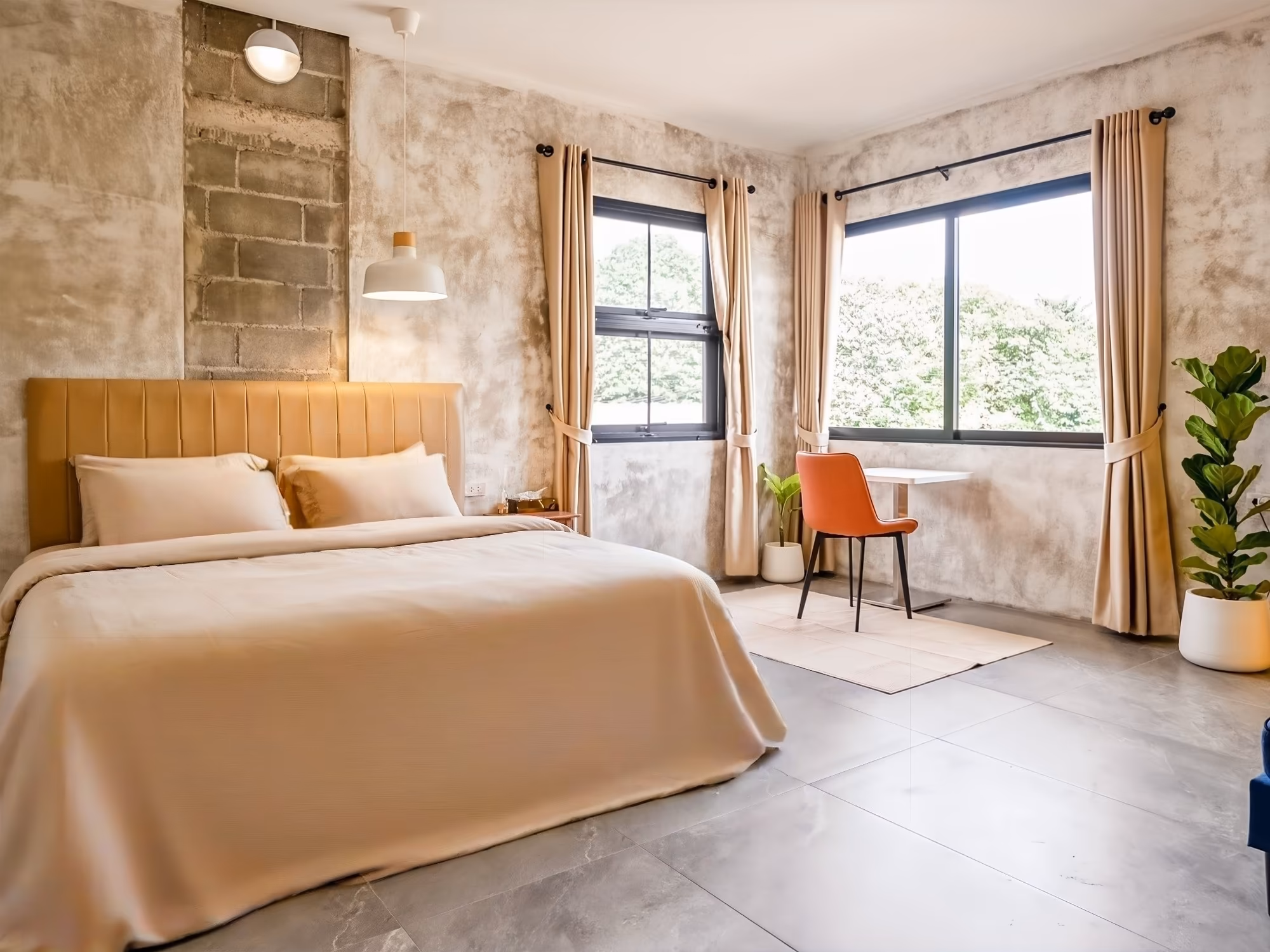 The Arch Casa Pai Superior Studio bedroom with queen bed, polished concrete walls, twin windows and orange desk chair