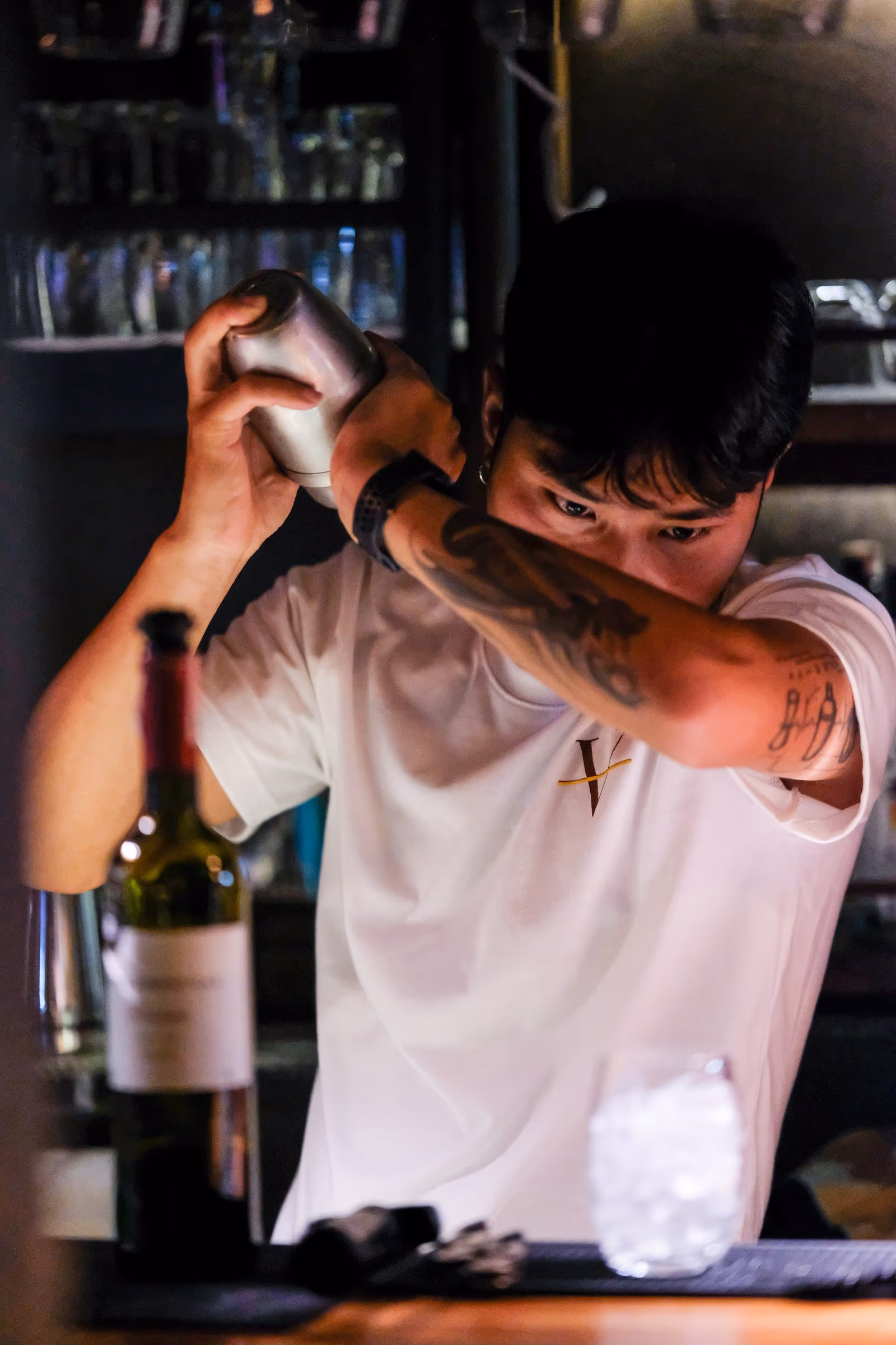 The bartender behind the bar at Vermut Café, Pai, lifting a bottle of wine