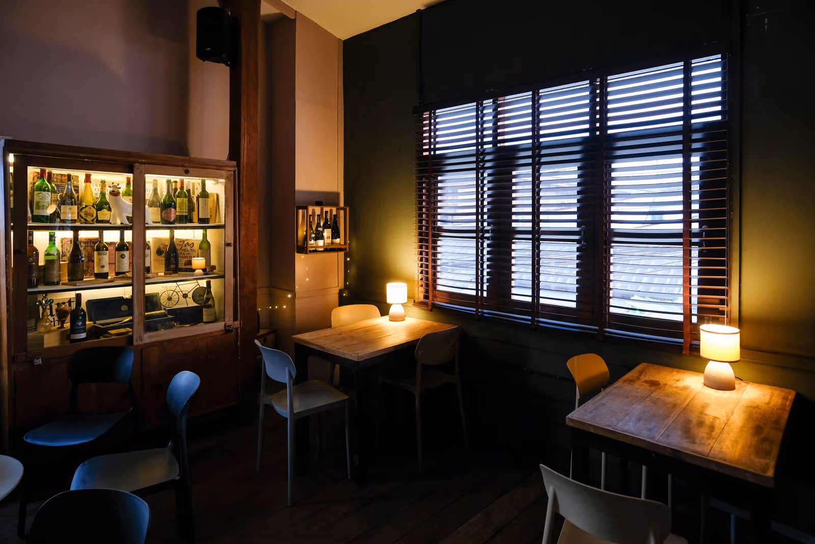 A table by the window at Vermut Café, Pai, with a lamp and the glass cabinet of wine behind