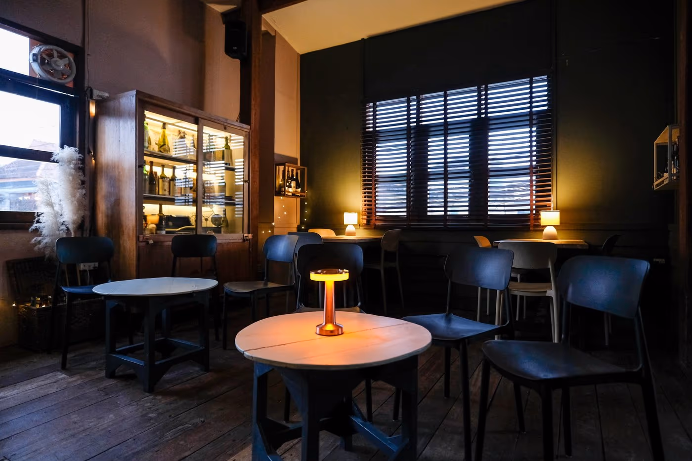 The upstairs lounge at Vermut Café, Pai — air-conditioned room with round tables and lamps