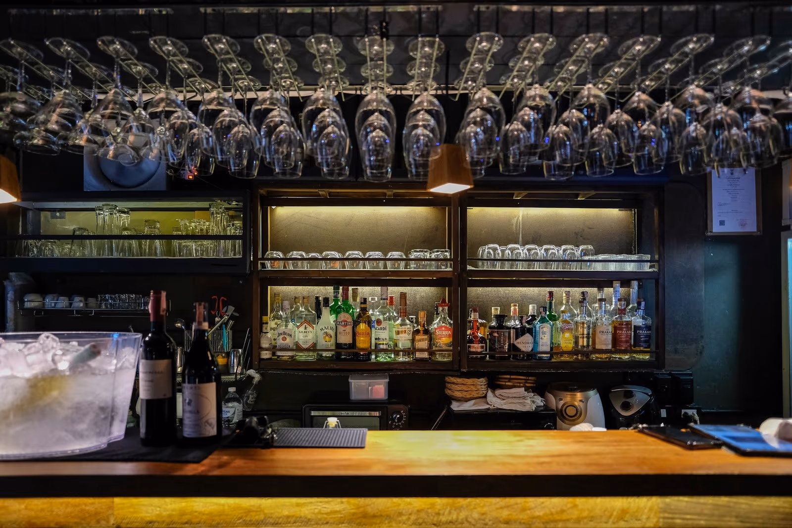 The bar at Vermut Café, Pai — glasses hanging above the counter and the back shelf of spirits and wine
